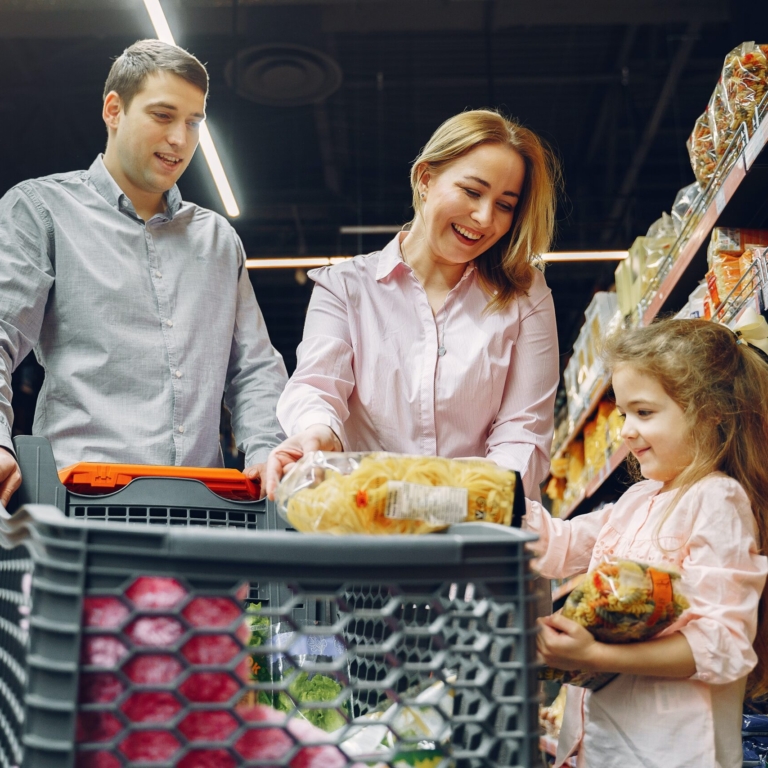 Um homem, uma mulher e uma criamçano supermercado, a criança segura produtos e os pais olha para ela